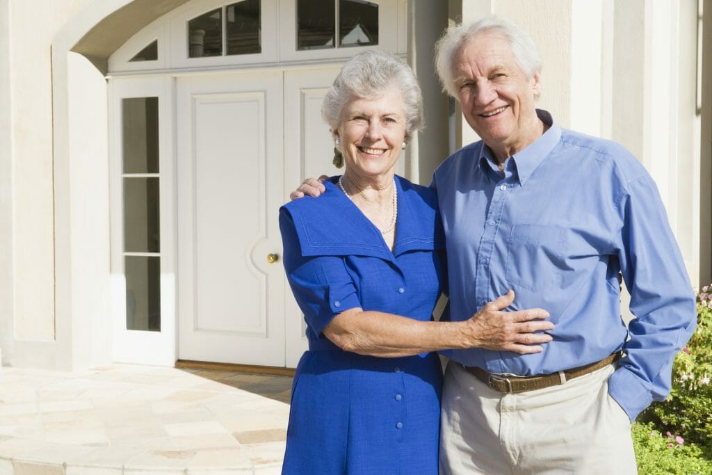 Older adult couple standing outside a home