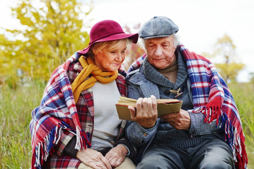 a senior couple reading a book together outdoors 