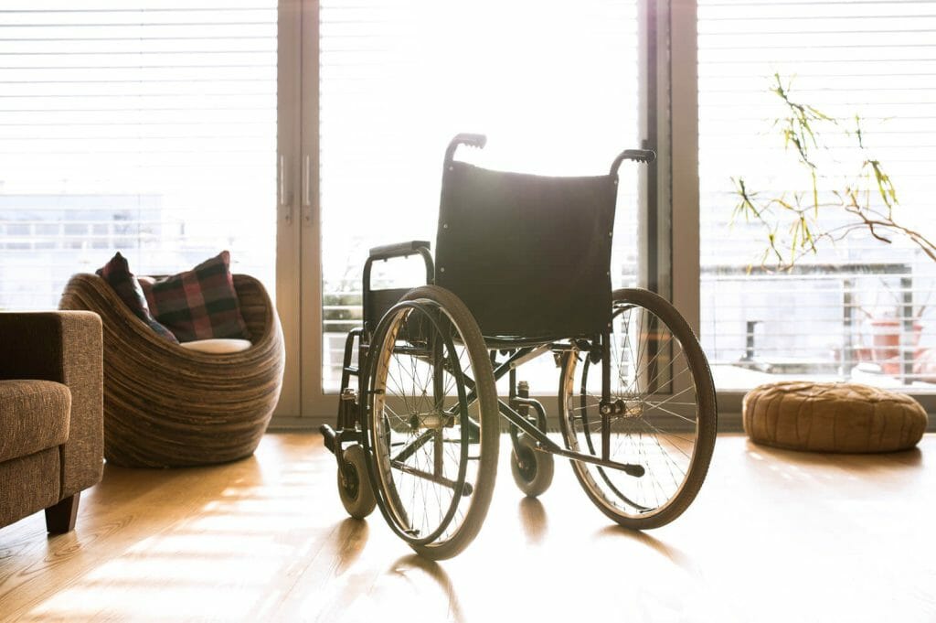 image of an empty wheel chair in front of a sunny window and door