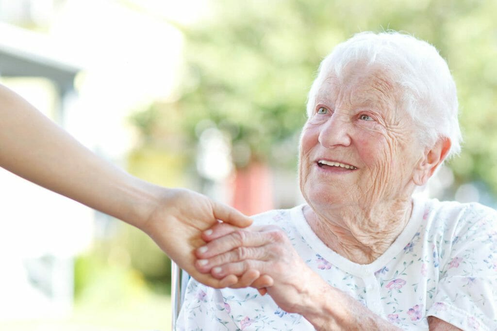 elderly woman holding the hand of her care giver.