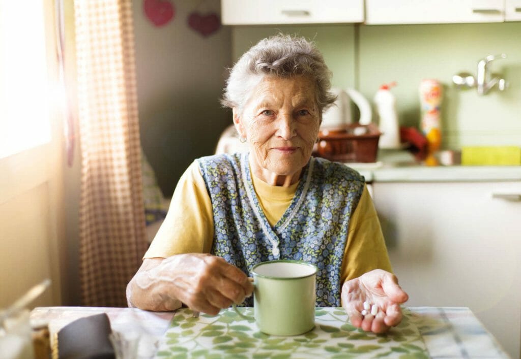 older woman taking her medication in her kitchen