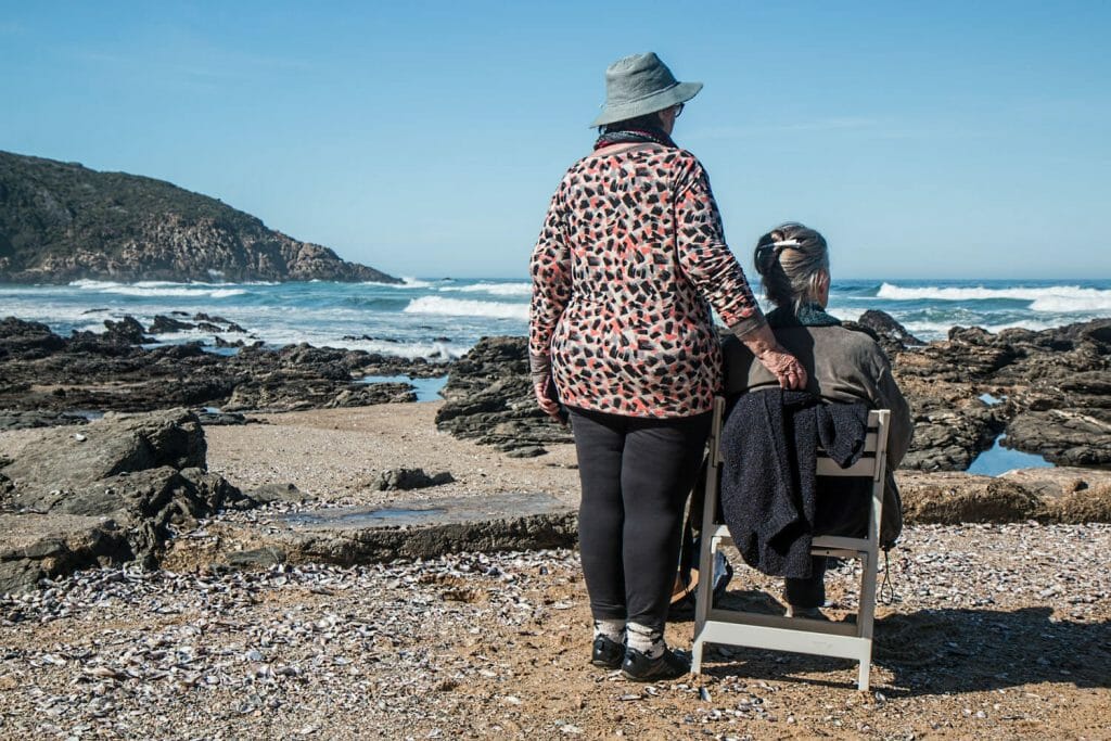 older woman sitting in a chair looking out at the ocean