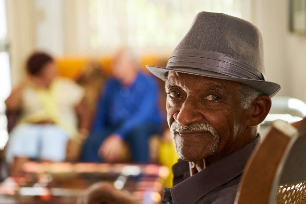 older man sitting in a community area within an assisted living facility.