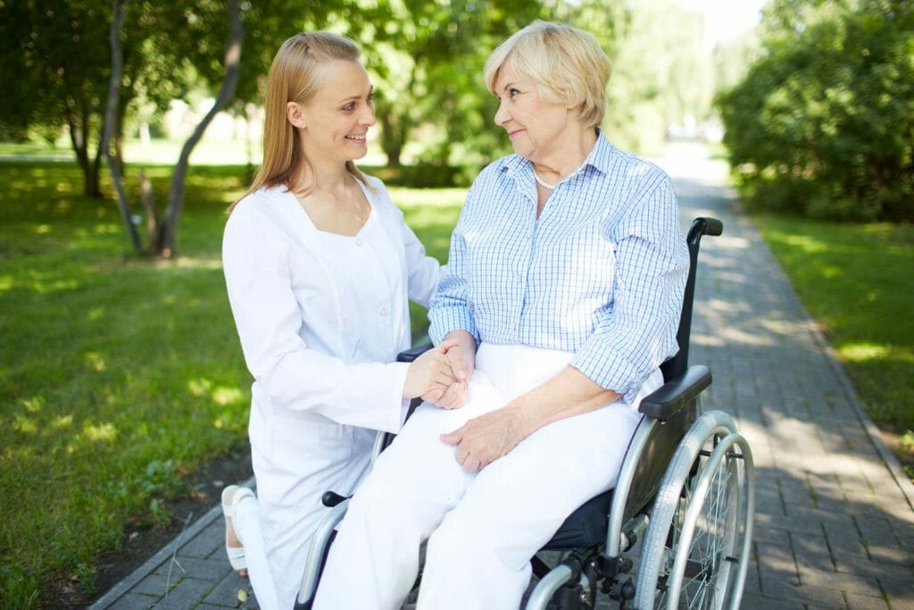 care giver sitting with an older woman in a wheel chair